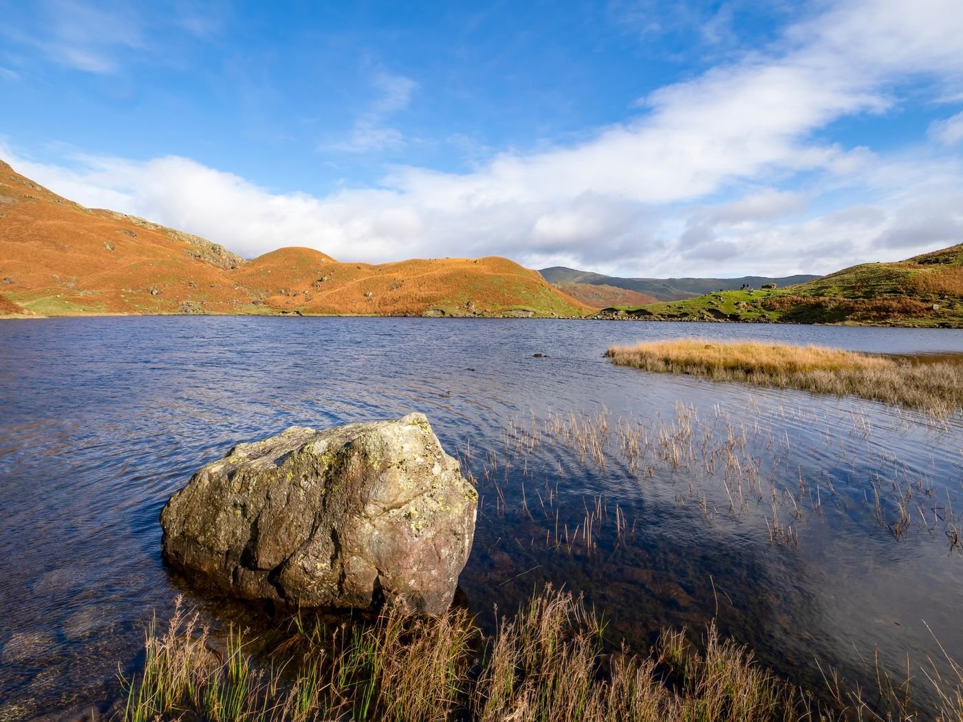 A Lake District tarn ringed by fells under a clear sky