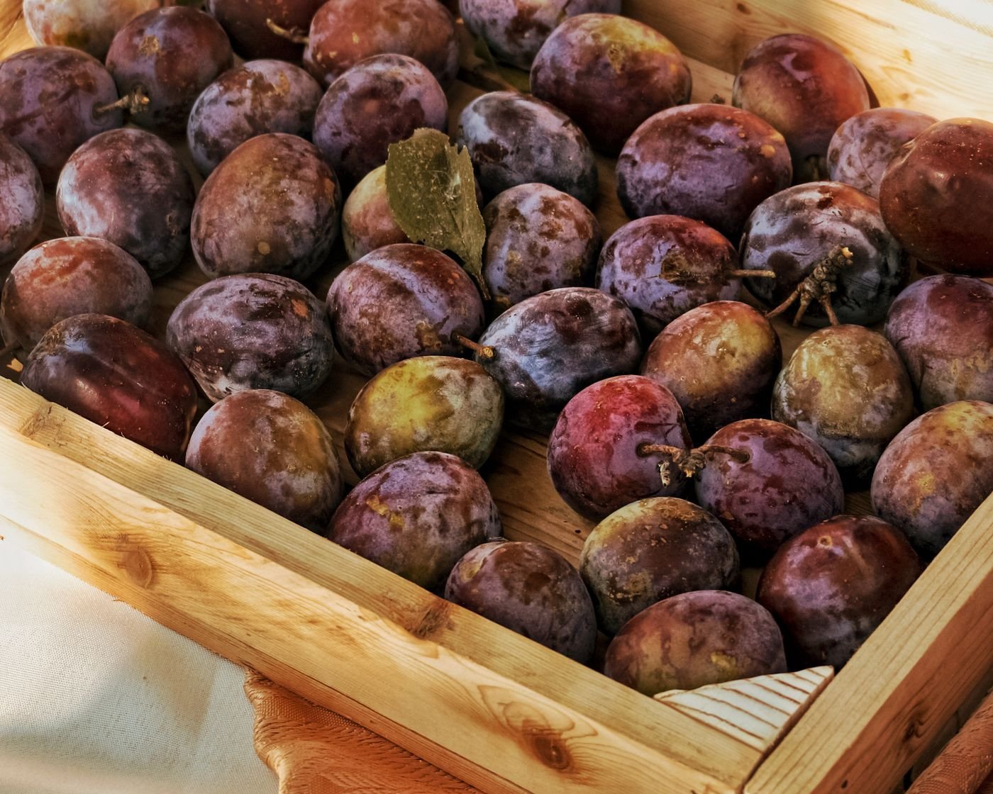 Ripe plums in a wooden crate