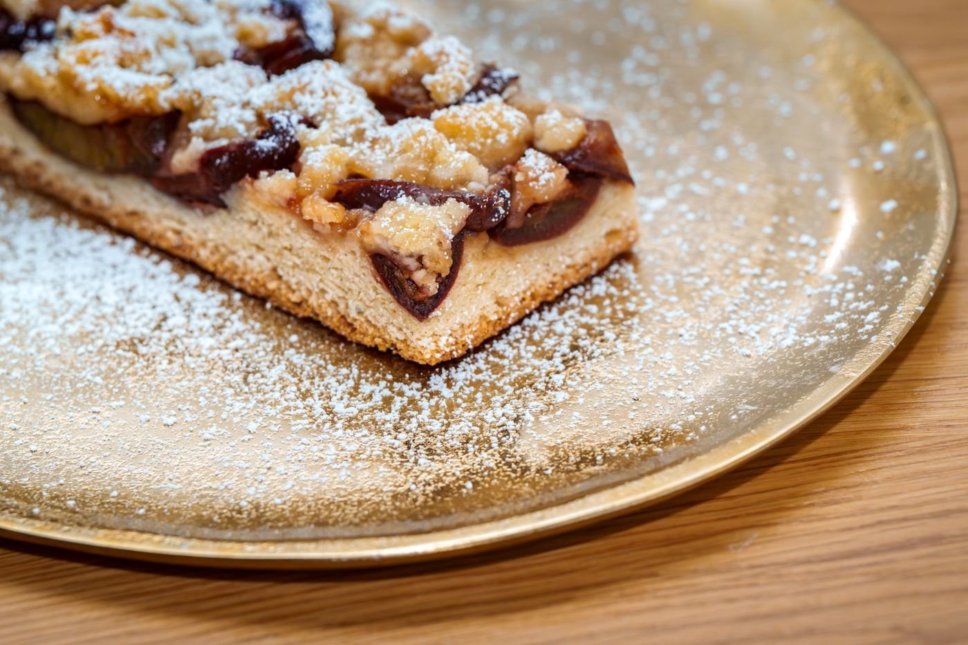 A slice of fruit tart dusted with icing sugar